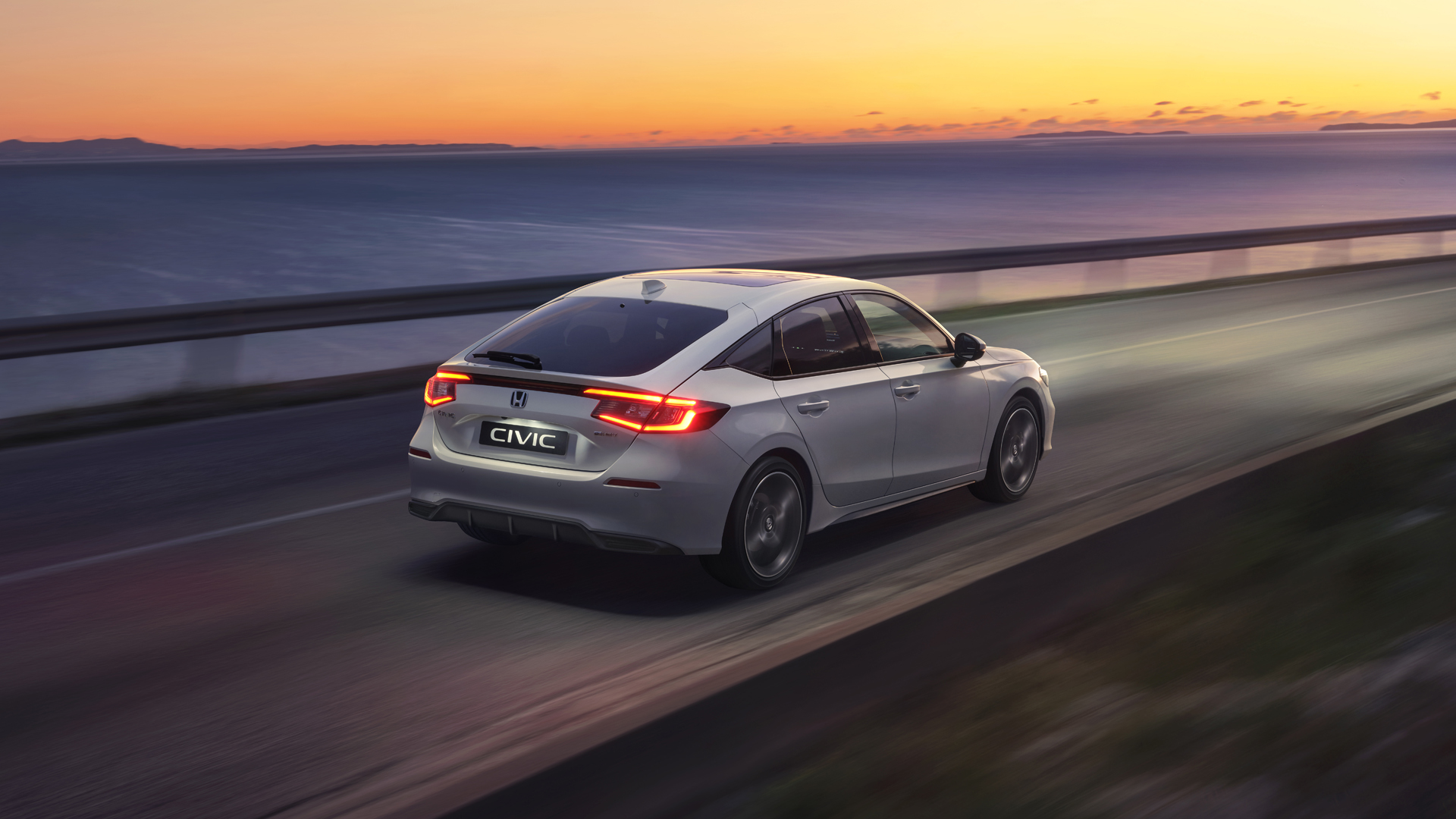 Voiture Civic Hybrid roulant au coucher du soleil.