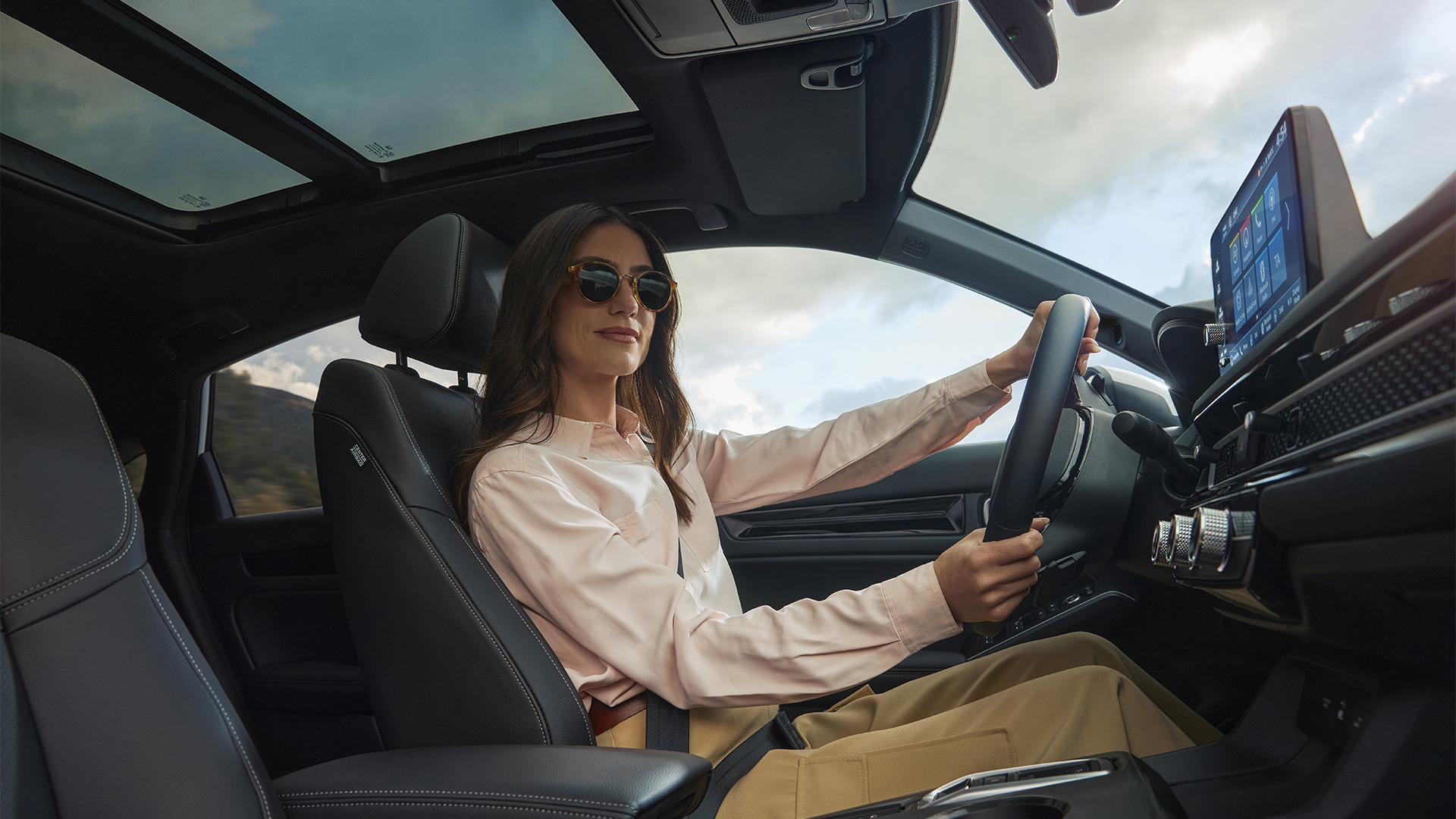 Une femme portant des lunettes de soleil, les mains sur le volant de la Civic Hybrid