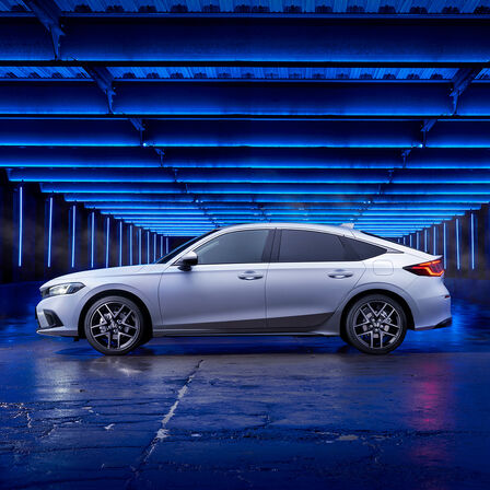 Vue de côté de la Honda Civic e:HEV garée dans une rue latérale.
