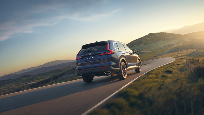 Vue latérale arrière du SUV hybride CR-V bleu en montagne.
