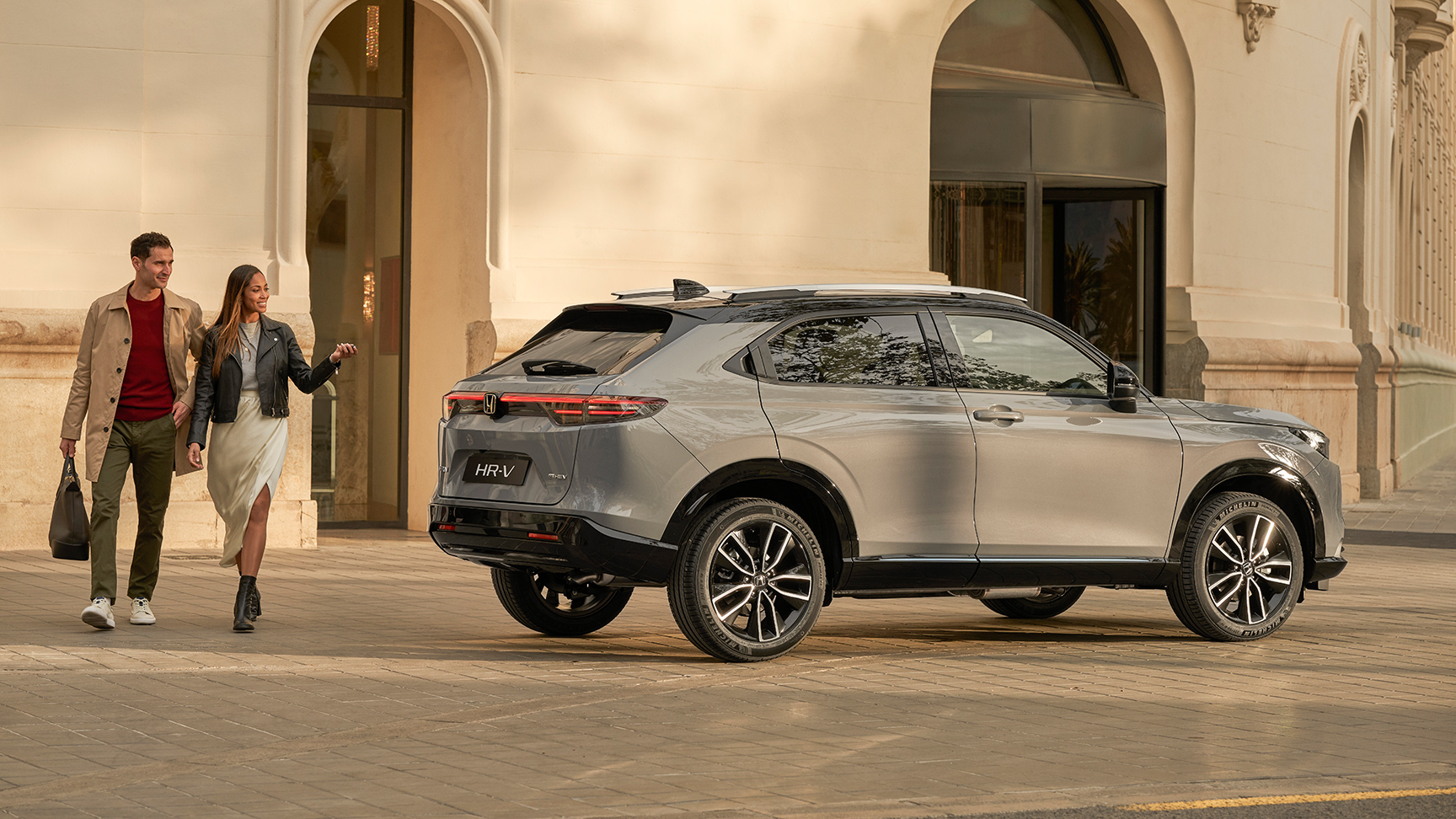 Couple marchant à côté d'un HR-V garé à l'extérieur d'un bâtiment. 