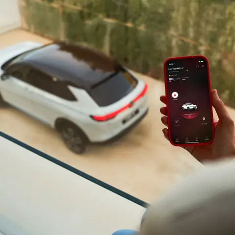 Gros plan d'une personne avec un téléphone utilisant l'application My Honda + avec Honda HR-V visible à travers la fenêtre