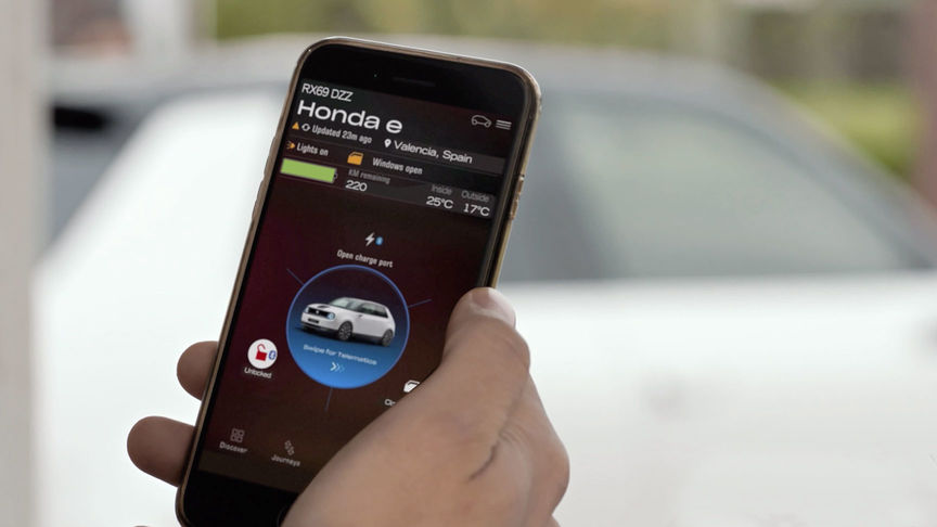 Man looking at My Honda Plus App with Honda Jazz Hybrid Crosstar behind. 
