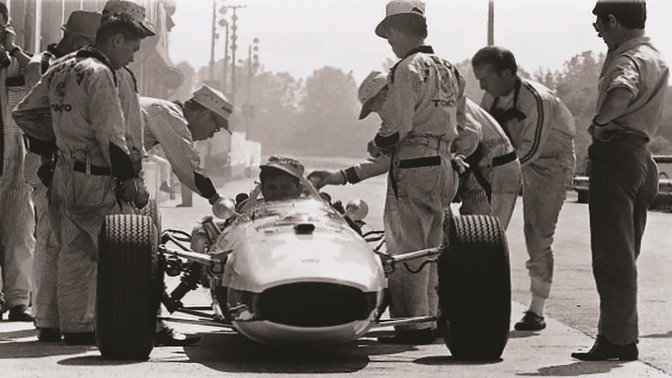 Vue avant de la voiture de Formule 1 Honda des années 1960 avec pilote et ingénieurs.