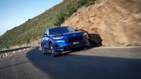 SUV ZR-V hybride de Honda circulant sur route en montagne.