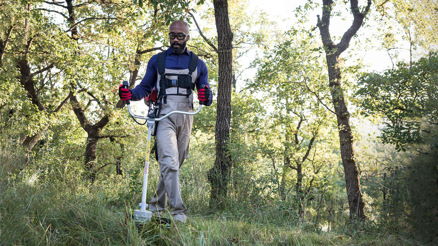 Débroussailleuse utilisée en forêt par un homme