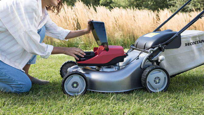 Femme utilisant une souffleuse dans un jardin