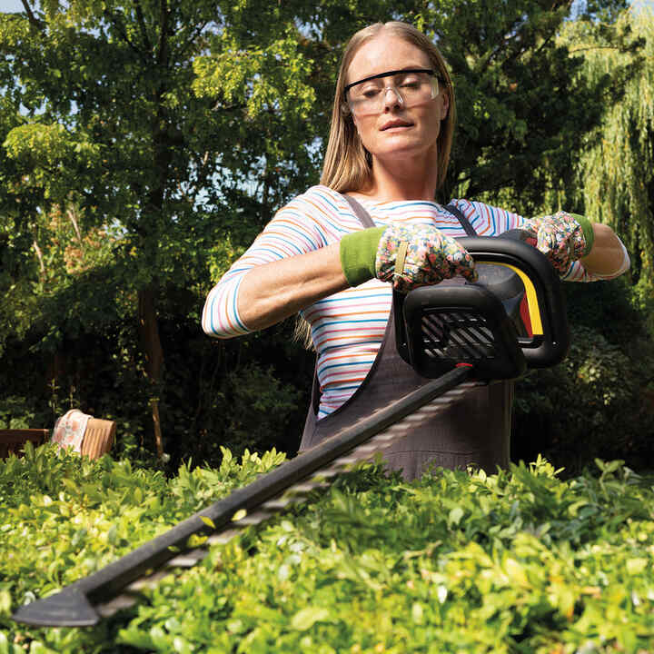 Femme utilisant une tondeuse à gazon dans un jardin