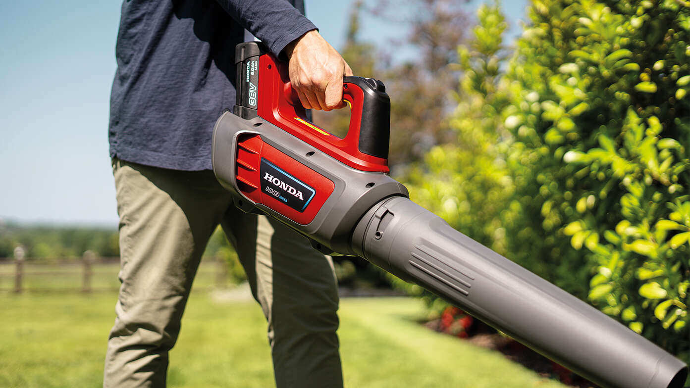 Homme tenant et utilisant un souffleur à batterie