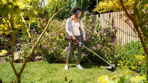 Femme utilisant le coupe-bordure à batterie Honda dans un jardin.