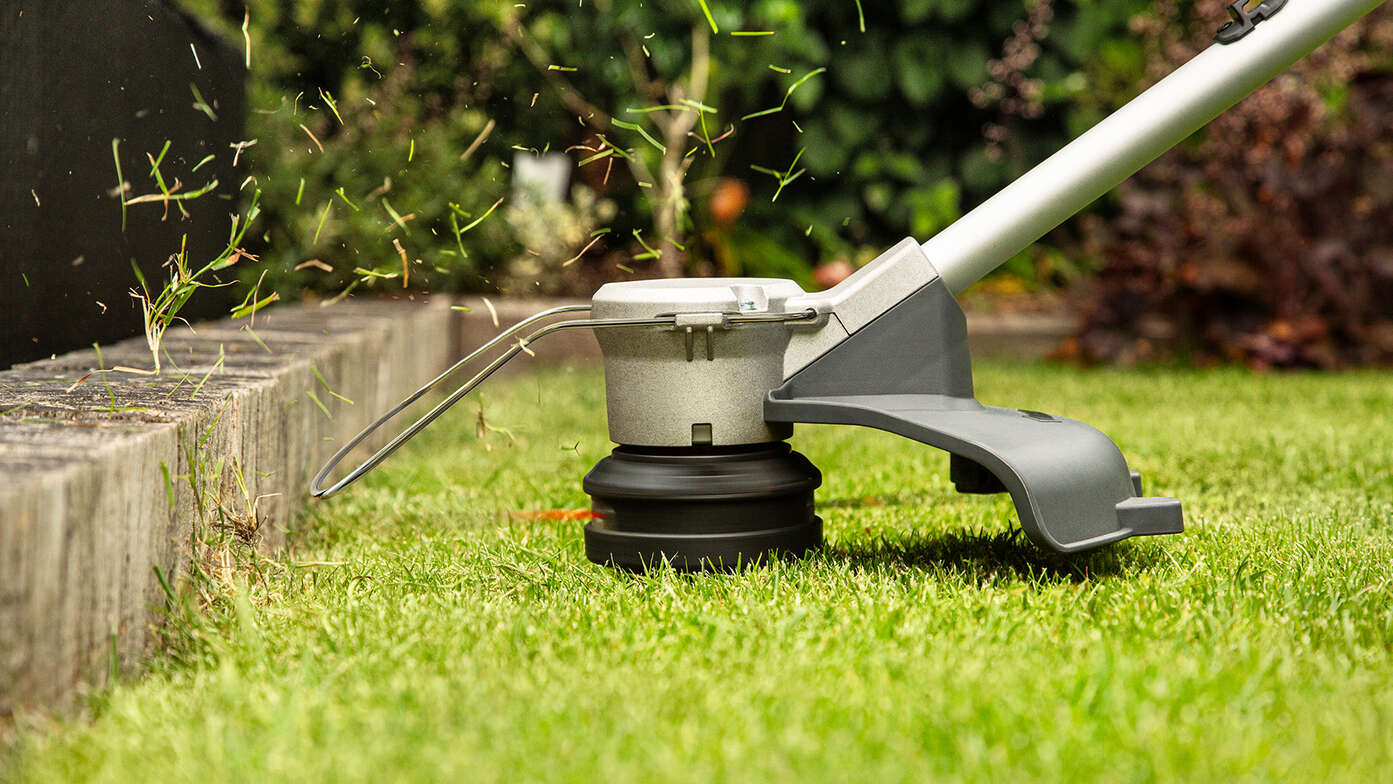 Coupe-bordure à batterie Honda en train d'égaliser le bord de la pelouse d'un jardin.