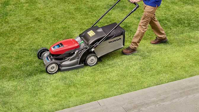 Homme poussant une Honda HRX dans un jardin. 