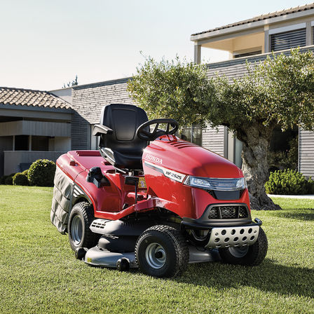 Vue de trois quarts face de la tondeuse Honda dans un jardin avec une maison en arrière-plan