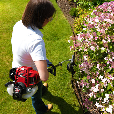 Honda Versatool™, plan sur un moteur 4-temps, utilisé par un démonstrateur, dans un jardin.
