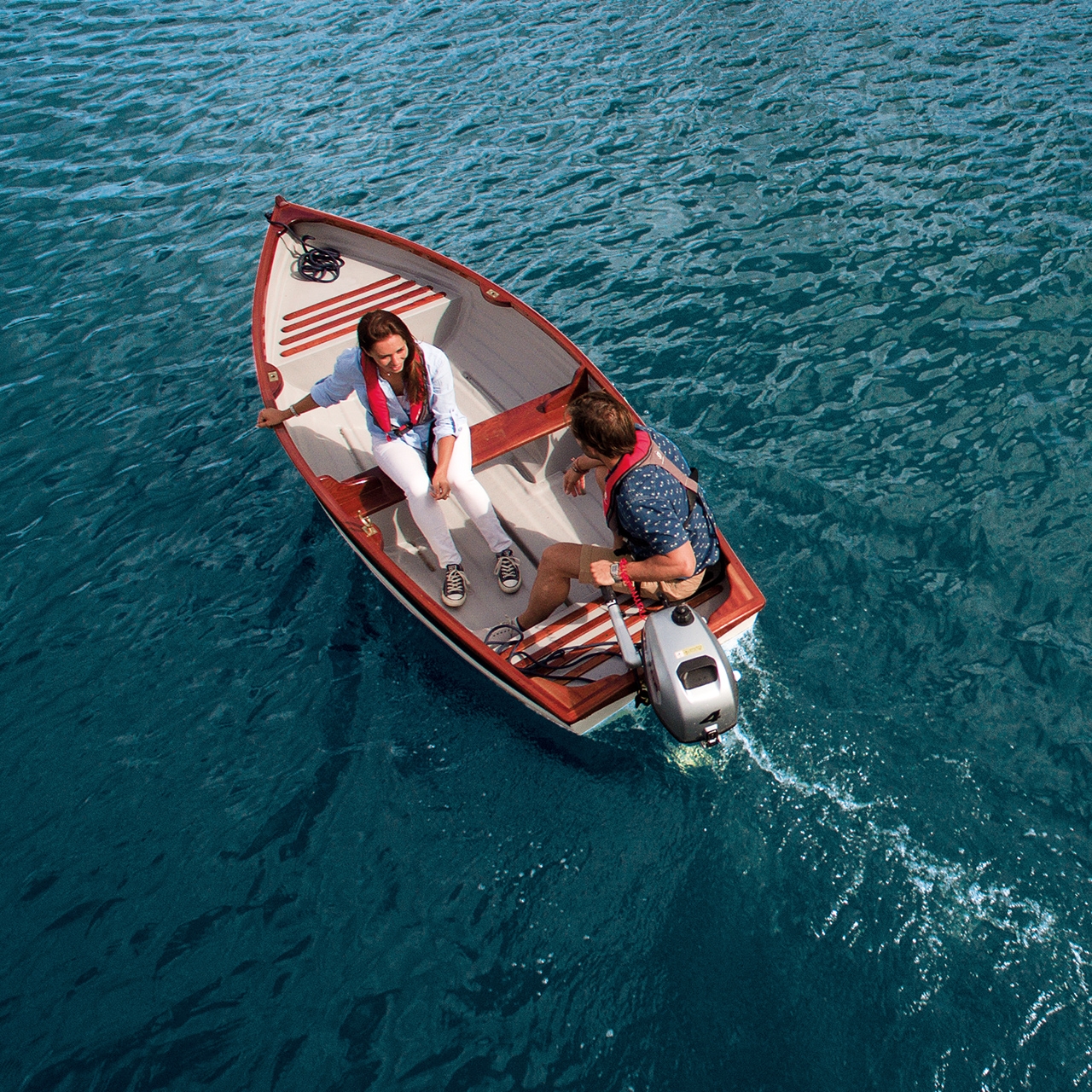 Couple sur un bateau avec moteur Honda sur l'eau.