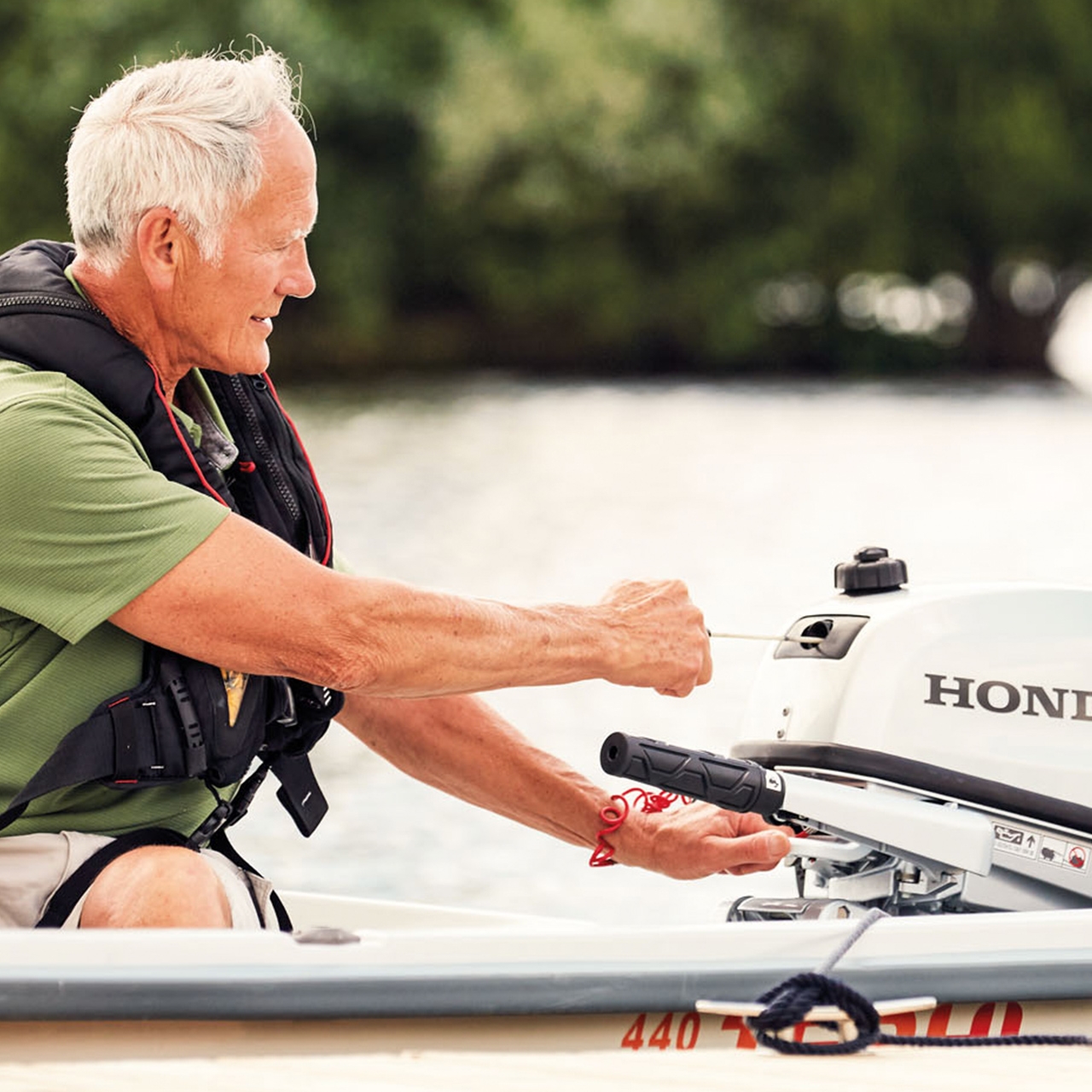 Monsieur sur un bateau démarrant un moteur Honda BF5.