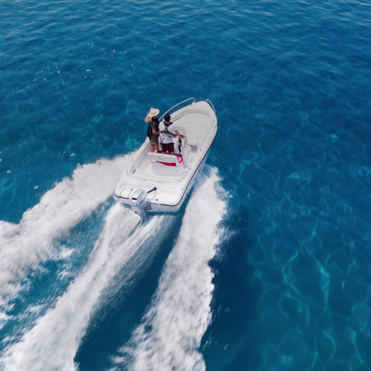 Couple sur un bateau dans l'océan avec un moteur Honda BF.
