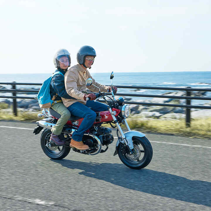 Honda Dax 125 sur une route côtière avec pilote et passager