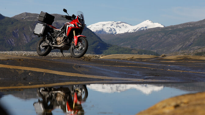 Africa Twin garée à côté d'une rivière au débit rapide en Norvège