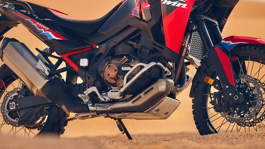 Mannequin roulant à bord d’une moto CRF1100L Africa Twin dans un environnement désertique.