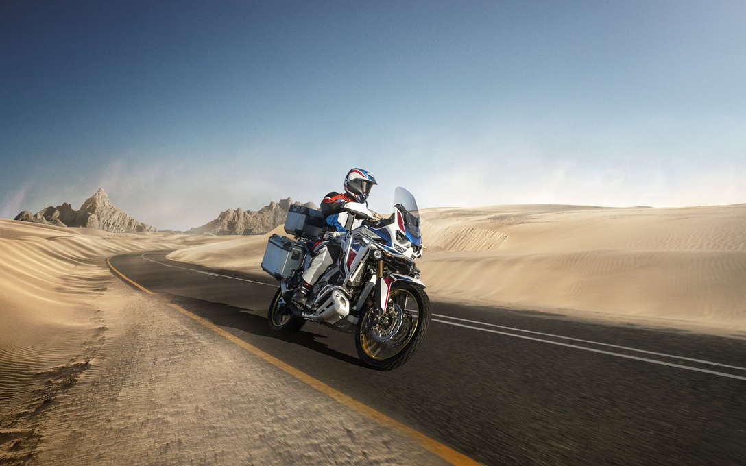 Trail Honda Africa Twin Adventure sports, vue de trois quarts avant droit, piloté sur une route dans un paysage désertique