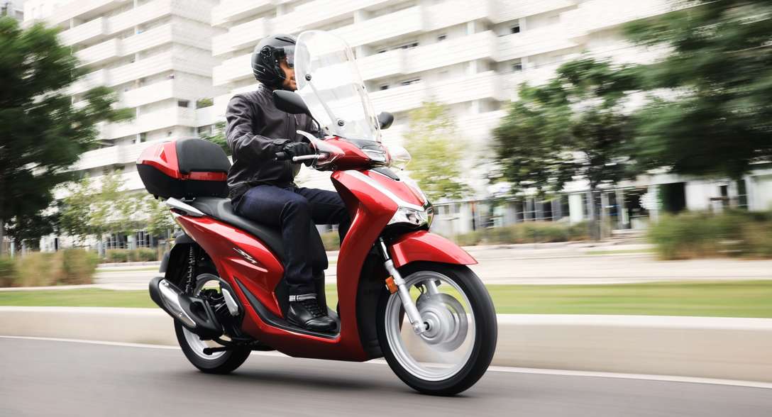 Vue de trois quarts avant droit du Honda SH125i, avec conducteur en ville