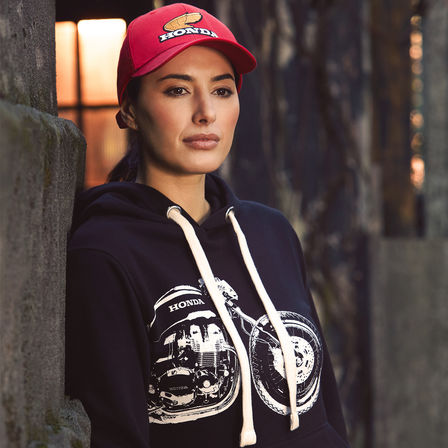 Femme portant un sweat à capuche et une casquette vintage Honda. 
