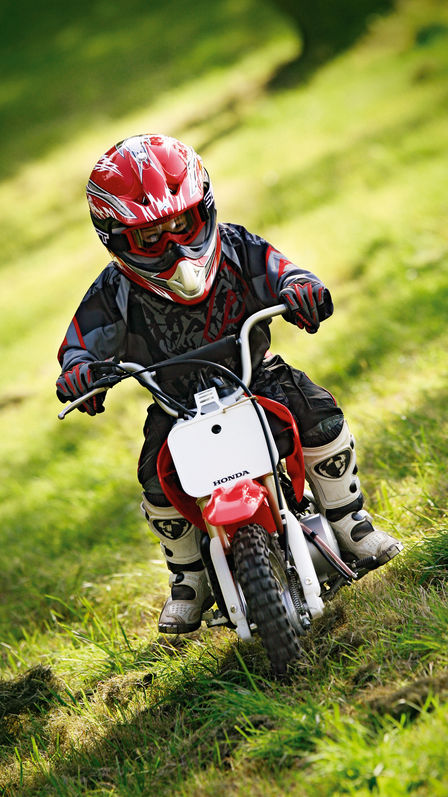 Vue de face de la CRF50F, avec conducteur sur terrain herbeux en pente.