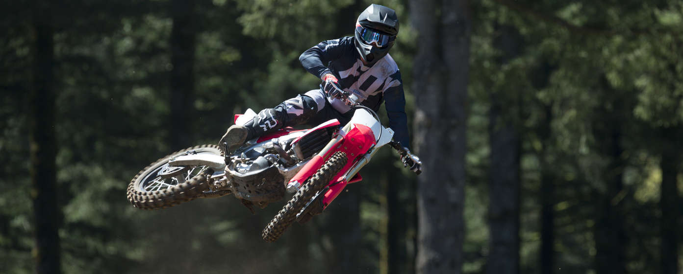 Vue de face de la moto CRF450R et de son pilote en plein saut.