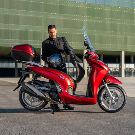 Vue arrière du Honda SH350i, rouge, avec un homme debout à côté du scooter