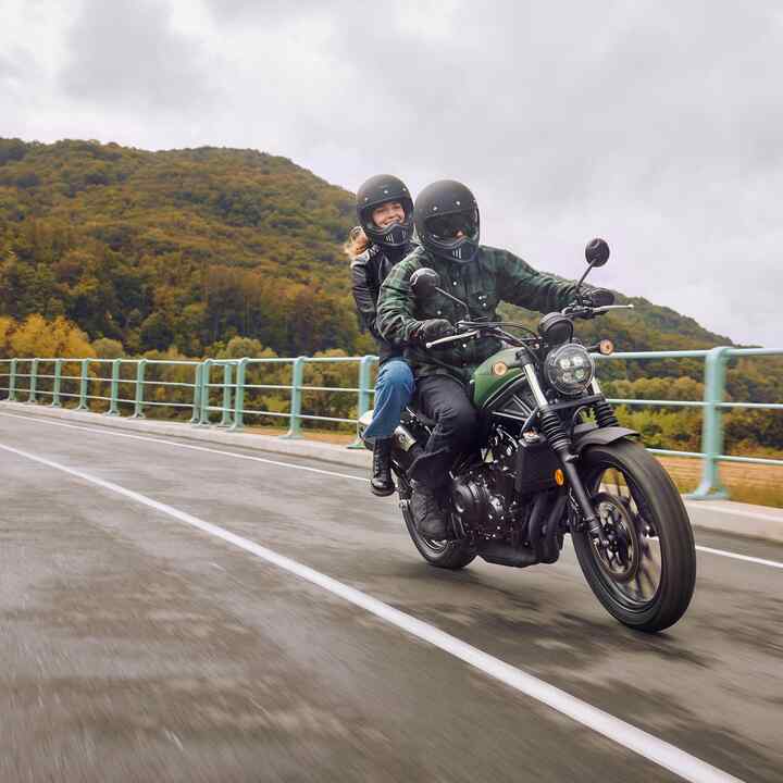 Honda CL500 sur une route avec un pilote et un passager.