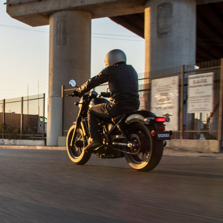 Vue de trois quarts arrière de la Honda moto custom permis A2 CMX500 et son pilote dans la rue.