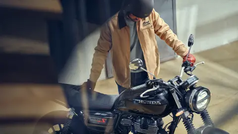 Plan ¾ avant d'une GB350S avec un pilote masculin dans un lieu de type café