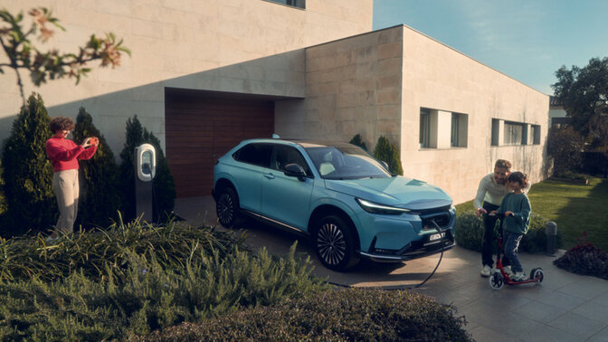 Vue de trois quarts avant de la Honda e garée devant un bâtiment de nuit